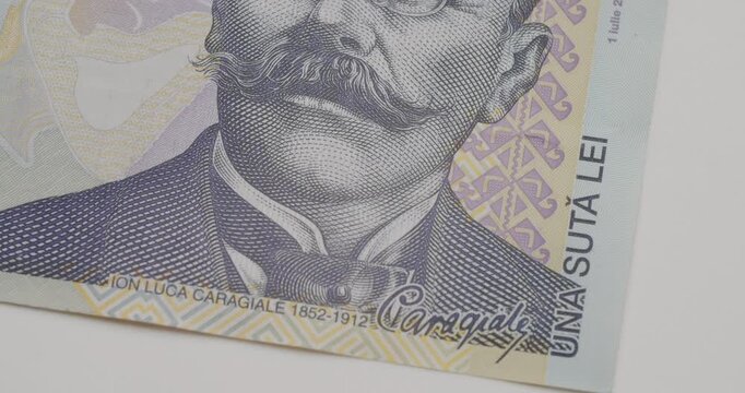 Close-up details of the Romanian one hundred lei banknote, featuring the portrait of playwright Ion Luca Caragiale, the National Theatre, and various security and artistic elements