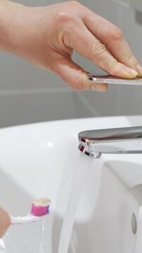 Woman open tap for toothbrush, dental hygiene and gum care at home. Closeup, brush teeth and rinse oral product for fresh grooming, morning routine and clean at bathroom sink.Water saving concept
