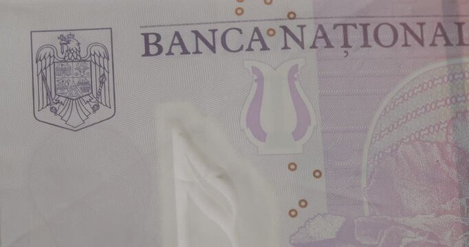 Extreme close-up of the Romanian five lei banknote, featuring composer George Enescu and the Romanian Athenaeum. Detailed macro view of the national currency, showing security features and artwork
