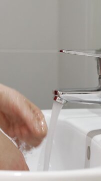 A close up of a woman washing her hands with soap and turning off the tap to save water in the bathroom.Water saving concept