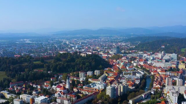 Aerial drone view of Ljubljana Castle hill, the old town along the Ljubljanica River, and city skyline with the Kamnik Alps behind in Ljubljana, Slovenia, autumn.