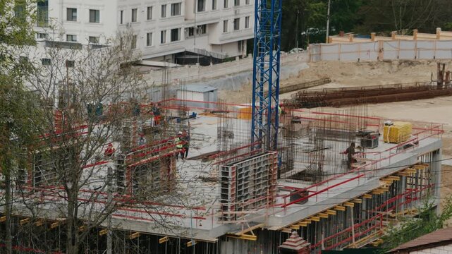 Time-lapse showing builders working on a construction site, reinforcing steel bars and pouring concrete for the foundation and walls of a new commercial building in an urban area