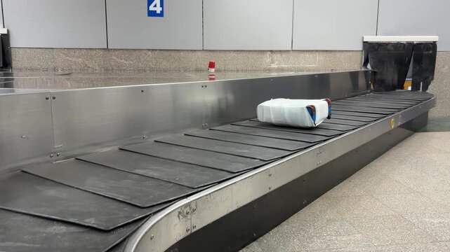 Light Blue Case On Conveyor Belt. Compact Blue Suitcase Slides Along Empty Baggage Claim Area