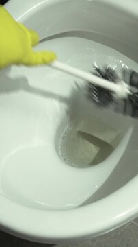 Scrubbing and cleaning. Shot of a woman hand with yellow glove cleaning a bathroom toilet.