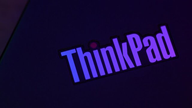 Close up of ThinkPad laptop logo with blinking red led indicator on cover under changing colorful RGB light.