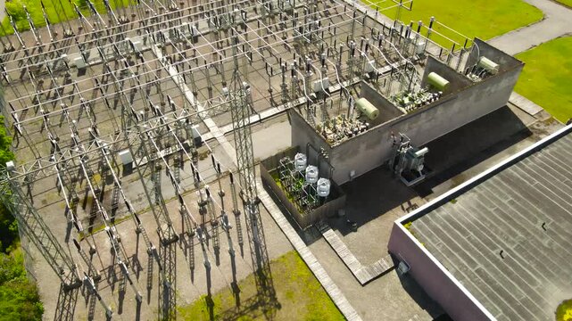 High voltage electrical power plant generating and distributing electricity with complex network of cables, towers, insulators, and transformers for energy supply on a sunny summer day