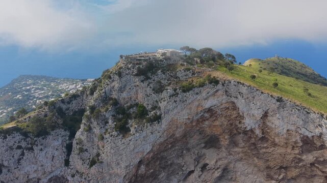 Aerial Drone View of Villa Jovis Ancient Roman Ruins on Monte Tiberio Summit Capri Island Italy, Dramatic Clouds and Town Below