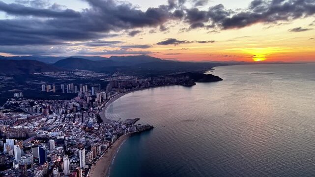 Sunset over curved bay skyline, drone panorama capturing coastal cityscape, highrise buildings hugging