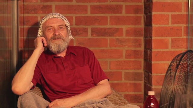 Elderly man struggling with extreme summer heatwave on his city apartment balcony