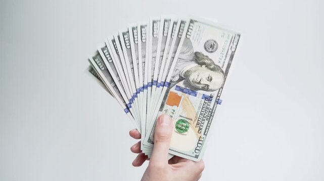 Female hands waving a stack of dollar bills against a white background. Conceptual concepts of cash payments, savings, financial planning, investing, and money management.