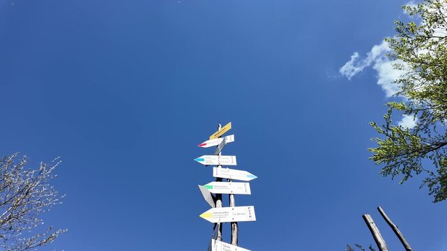 A wooden trail signpost on Magurka mountain under a blue sky.