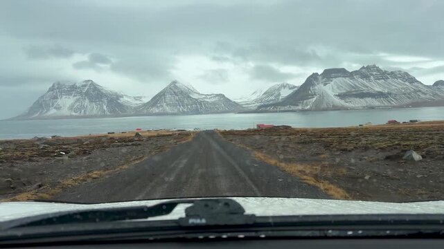 Car Driving Through Unpaved Road Leading Toward The Fjord With Snowy Mountains In Gjogur, Iceland. - POV shot