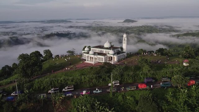 Drone view of Sajek Valley mosque, tourist vehicles, and a sea of clouds