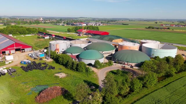High angle drone mapping shot of a bioenergy facility featuring multiple fermentation domes, storage silos, and surrounding fields in Bavaria