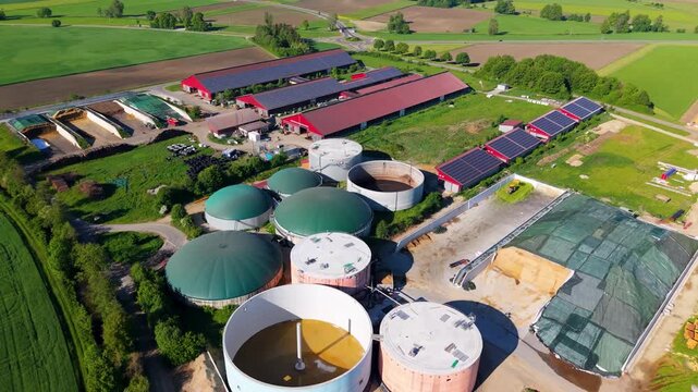 High angle drone mapping shot of a bioenergy facility featuring multiple fermentation domes, storage silos, and surrounding fields in Bavaria