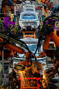 Robotic arms are welding body weld points on an automated production line at an automobile factory.