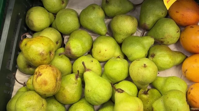 Green pears lie packed together in a deep crate under bright store lighting, a clean overhead view suited to themes of fresh fruit and everyday shopping.