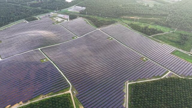 Aerial drone view of a large ground-mounted solar panel farm with access roads.