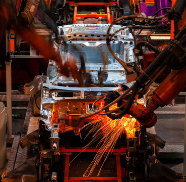 Robotic arms are welding body weld points on an automated production line at an automobile factory.