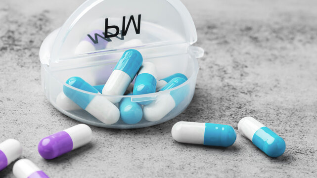 Pastel blue and white capsule pills spilling from open daily pill organizer on a grey concrete background. Healthcare and medication concept