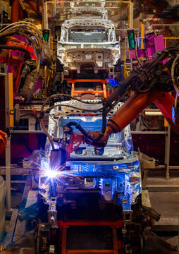 Robotic arms are welding body weld points on an automated production line at an automobile factory.