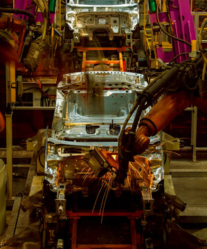Robotic arms are welding body weld points on an automated production line at an automobile factory.