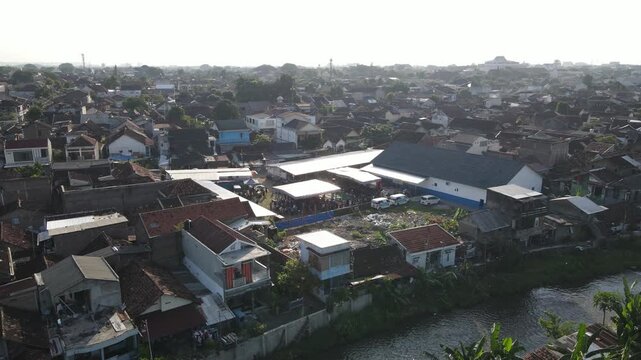 Aerial footage of a crowd of residents watching a traditional dance, amidst the density of an urban village, Yogyakarta, Indonesia.