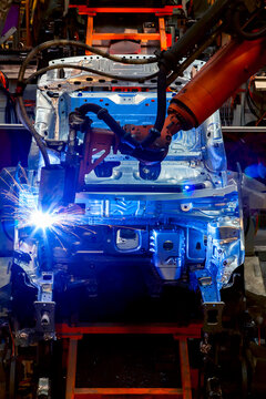 Robotic arms are welding body weld points on an automated production line at an automobile factory.