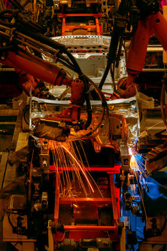 Robotic arms are welding body weld points on an automated production line at an automobile factory.
