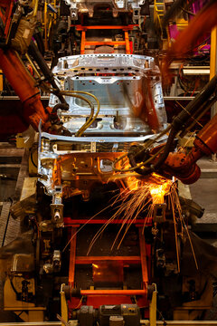 Robotic arms are welding body weld points on an automated production line at an automobile factory.