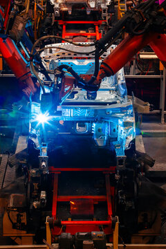 Robotic arms are welding body weld points on an automated production line at an automobile factory.