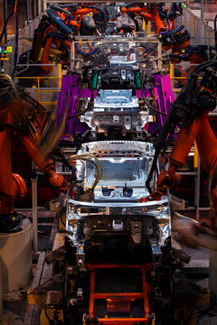 Robotic arms are welding body weld points on an automated production line at an automobile factory.