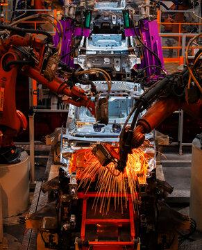 Robotic arms are welding body weld points on an automated production line at an automobile factory.