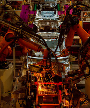 Robotic arms are welding body weld points on an automated production line at an automobile factory.