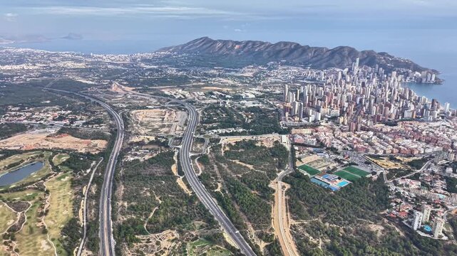 Winding highways and urban sprawl toward coastline and skyline, green corridors, interchange junctions