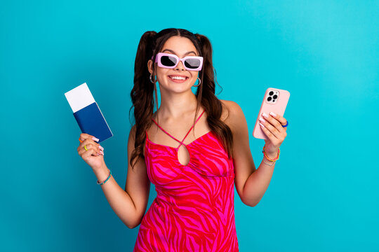 Young chic female model wears pink zebra dress smiles with phone and card against blue background for stylish shopping lifestyle