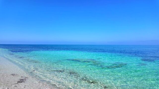 Amazing turquoise gradient water at Is Arutas beach in Sardinia, Italy. Wide angle view of crystal clear vibrant sea and white quartz sand coast under a clear blue sky