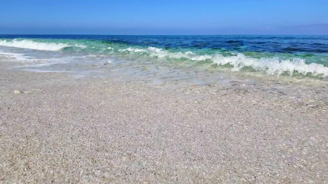 Turquoise sea waves crashing on white quartz sand at Is Arutas beach in Sardinia, Italy. Crystal clear water washing the shoreline under a bright blue sky