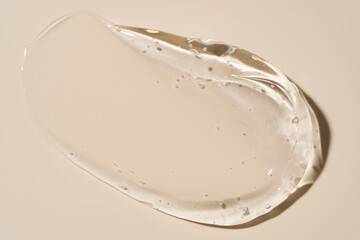 Transparent Clear Cosmetic Gel Swatch with Bubbles on Pastel Beige Background Close Up Top View
