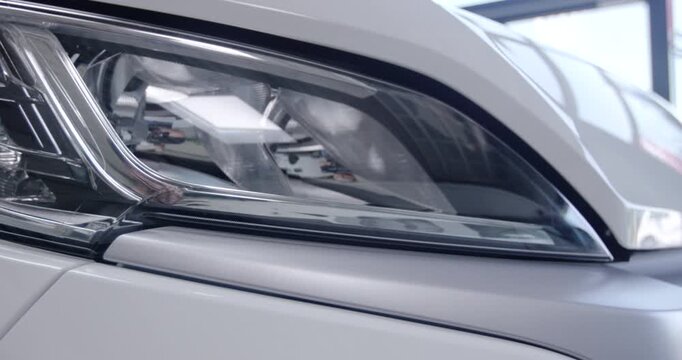 Close up detail view of a modern car headlight on a white vehicle body