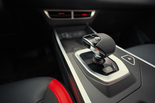 Modern automatic gear shifter on the center console inside a luxury car cockpit with selective focus.