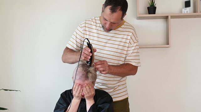 woman cries over hair loss while husband helps wife shave hair which is falling out due to chemotherapy for breast cancer. Breast cancer treatment and depression psychological aspect of oncology