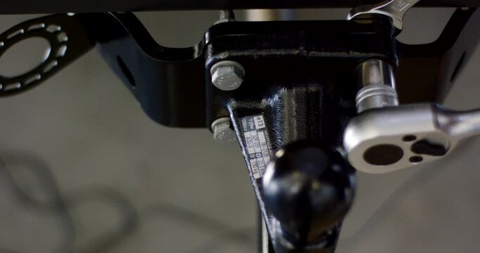 Top view close up of a socket wrench tightening a bolt on a black metal tow hitch