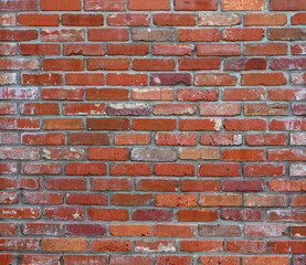 Fototapeta premium Horizontal close up of a reclaimed red brick and mortar wall surface with worn chipped cracked bricks, porous uneven mortar, weathering signs, water spots, and white deposits