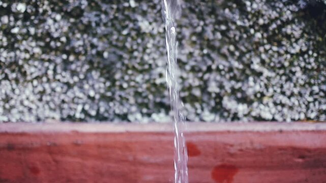 Inquadratura ravvicinata di flusso di acqua corrente limpida e fresca su uno sfondo fuori fuoco in luce naturale