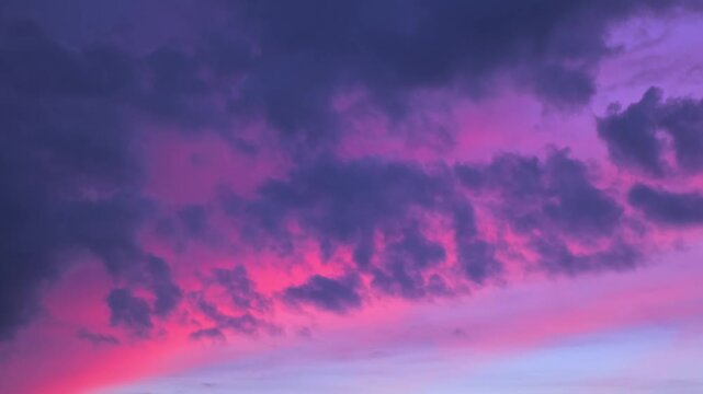 Morning or evening sky. Colorful clouds fill twilight with gradients of purple and pink during sunset or sunrise. Natural background. Beauty in nature. Expressive cloudscape. High quality 4K footage.