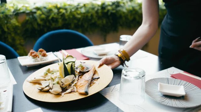 Professional waitress with tattoos serving a beautifully arranged gourmet seafood dish with salmon and clams at an elegant sushi restaurant