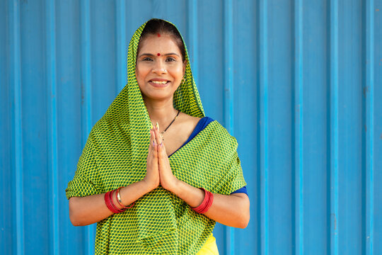 Smiling Indian rural woman in a traditional saree greeting with folded hands (Namaste) while looking at the camera. Concept of Indian culture, hospitality, respect, women empowerment, self-help groups