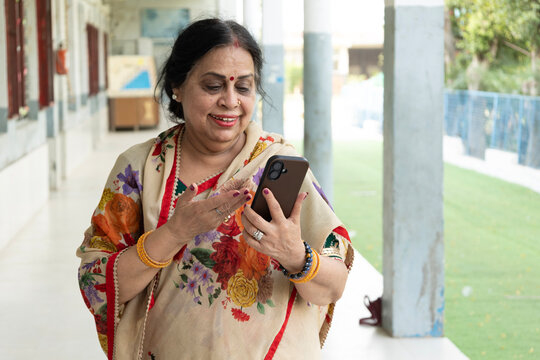 Experienced Indian NGO professional having a phone conversation, smiling confidently while coordinating community programs, showcasing women's leadership, social impact, communication