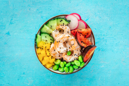 Poke bowl with shrimps, tomatoes, cucumber, mango, edamame, and radish